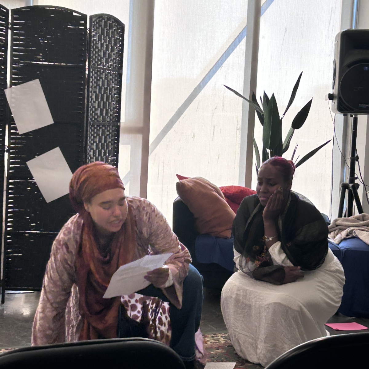 Two actors from Amelie's play, Gathering,
                    crouch in the middle of a scene.